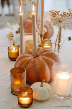 candles and pumpkins are arranged on a table