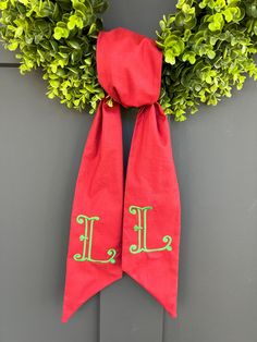 a red scarf hanging on the side of a gray door with green leaves around it