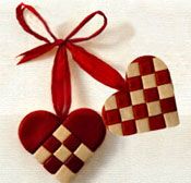 two red and white heart shaped ornaments hanging from a ribbon