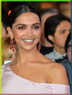 a woman in a pink dress smiling at the camera