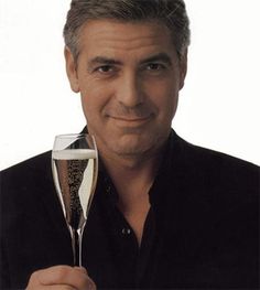 a man holding a glass of wine in his right hand and smiling at the camera