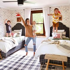 a woman and two children jumping in a bedroom