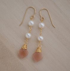 Add a subtle touch of elegance to your look with these beautiful Peach Moonstone and Freshwater Pearl dangle earrings. With their warm, peachy tones and soft pearls, these earrings feel inviting and calming and are perfect for weddings or special occassions.Peach Moonstone is known for aiding in the release of negative thinking and being overly self-critical. It's believed to be a stone of new beginnings, that brings balance and relief from emotional issues. The matching necklace is here.GEMSTON Elegant Apricot Earrings For Gift, Handmade Apricot Earrings In Elegant Style, Handmade Apricot Earrings Elegant Style, Gold Dangle Pearl Earrings With Natural Stones, Handmade Gold Plated Dangle Pearl Earrings, Handmade Elegant Apricot Earrings, Natural Stone Dangle Pearl Earrings, Elegant Apricot Dangle Jewelry, Elegant Apricot Dangle Earrings