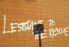 graffiti written on the side of a brick building reads lessons to the rescue, and it appears to be in white spray paint