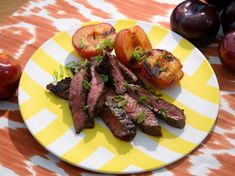 grilled steak and tomatoes on a yellow and white plate next to plums, peaches and an apple