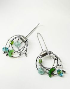 swagger?add these unique and modern earrings to your wardrobe. organic drop "orbit" dangle earrings in varying hues of seafoam, lime to teal blue-green vintage glass beads.  these earrings are fun, eclectic and whimsical in style. the beads are set individually on their own loop making each bead swing and dance giving them a nice kinetic vibe. the metal is oxidized sterling silver.  completely hand made by me in my studio in austin, texas. due to the handmade nature please allow for subtle differences. approximately 2" total length Unique Green Hoop Earrings, Green Drop Earrings With Unique Variations, Green Drop Wrap Earrings With Ear Wire, Green Wrap Drop Earrings With Ear Wire, Kinetic Earrings, Earrings Bohemian, Green Vintage, Bohemian Earrings, Green Earrings