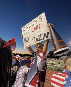 a young man holding up a sign at a football game