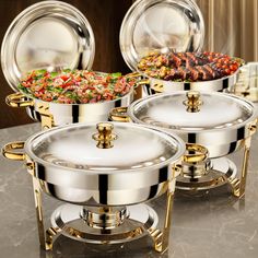 three silver pots with gold handles on a marble countertop and plates in the background