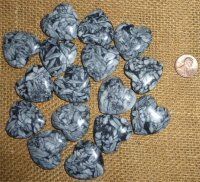 some rocks are sitting next to a penny on a tablecloth with a piece of cloth in the background