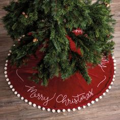 a christmas tree skirt with the words merry christmas written on it and pom - poms