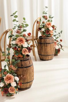 three wooden barrels with flowers in them sitting on a white floor next to chairs and drapes