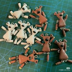 several small brown and white figurines are on a green cutting board next to scissors