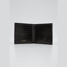 Saint Laurent wallet in smooth calf leather with metal YSL monogram in the corner. Interior: two bill compartments, eight card slots, two receipt pockets. Approx. 3.7"H x 4.3"W x 0.9"D. Made in Italy. Designer Business Trifold Wallet, Modern Bifold Wallet With Logo Plaque, Designer Trifold Wallet With Coin Pocket For Business, Designer Trifold Wallet With Interior Card Slots, Designer Trifold Wallet With Rfid Blocking For Business, Designer Bifold Wallets For Formal Occasions, Designer Trifold Wallet With Rfid Blocking For Formal Occasions, Classic Leather Wallets With Logo Plaque, Classic Leather Wallet With Logo Plaque