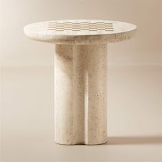 a white table sitting on top of a floor next to a beige wall with geometric designs