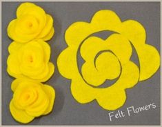 yellow felt flowers sitting next to each other on a gray surface with the word felt flowers written in white