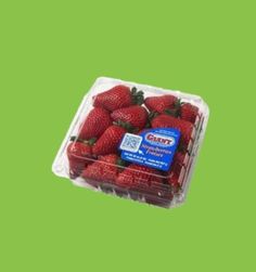 strawberries in a plastic container on a green background