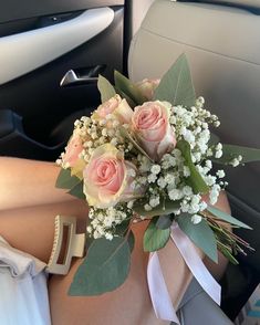 a bouquet of roses and baby's breath sits in the back seat of a car