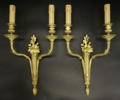 three golden candelabras with candles on them