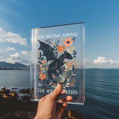 a hand holding up a clear book with an image of a dragon on the cover