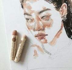 two crayons next to a drawing of a woman's face