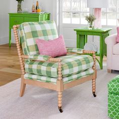 a living room with green furniture and pink pillows on the chair, white rugs