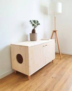 a wooden cabinet with a potted plant on top and a lamp next to it