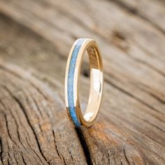 a wedding ring that is sitting on top of a piece of wood with blue and white stripes