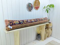 a bench with a long rug on it in a room filled with potted plants