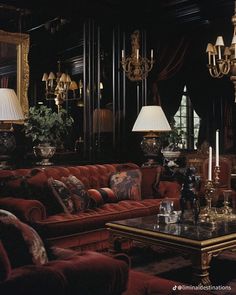 a living room filled with red couches and chandeliers on top of them