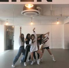 four young women posing for a photo in front of a mirror with their arms up