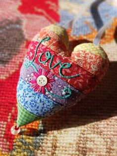 a colorful heart shaped ornament with the word love on it's side