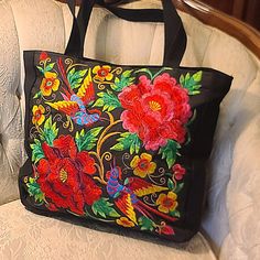 This gorgeous floral tote can easily go from casual to dressy. Colorful embroidered flowers and birds are featured on the front panel of the sturdy canvas bag with ample room to hold all of your everyday items. Approx. 13.5" X 17" bag with 12" handles Machine embroidered Canvas Material Fully lined with small pocket Zipper closure Bead Bag, Embroidered Tote Bag, Embroidered Canvas, Embroidered Tote, Crochet Purses, Beaded Bags, Everyday Items, Blue Bags, Embroidered Flowers