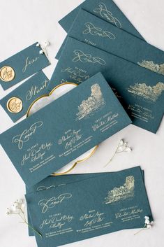 the wedding stationery is laid out on top of each other, with gold lettering