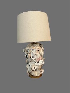 a lamp made out of seashells on a wooden base with a white shade