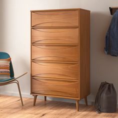 a wooden chest of drawers next to a blue chair