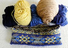 three skeins of yarn sitting on top of a blue and yellow bag next to each other