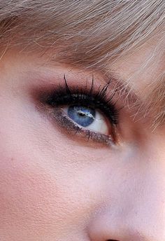 a close up of a woman's face with blue eyes and blonde hair, looking straight ahead