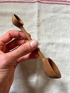 a person holding two wooden spoons in their hand