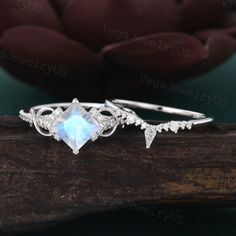 a ring with an opal stone surrounded by white diamonds sits on a piece of wood