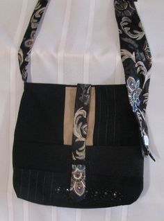 a black purse with an ornate design on it's side and a ribbon hanging from the front