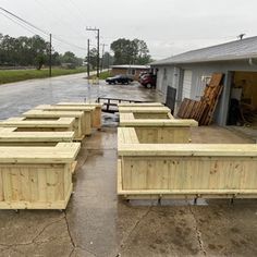 several wooden benches sitting in front of a building on the side of a road near a parking lot