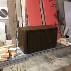 a brown box sitting on top of a wooden floor next to boxes and plywood