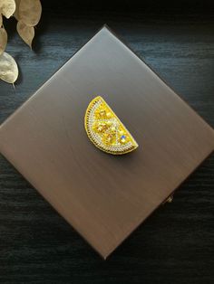 a yellow brooch sitting on top of a wooden table