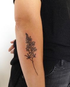 a woman's arm with a small flower tattoo on the left side of her arm