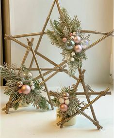 a star made out of branches with ornaments on it and other decorations around the base