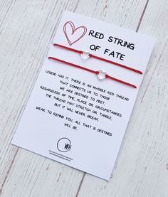 two red string bracelets with heart charms on white wood planked background that says, red string of fate