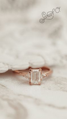 an engagement ring with a diamond in the center on top of a white marble surface