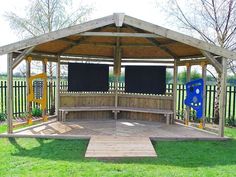 a wooden gazebo sitting on top of a lush green field