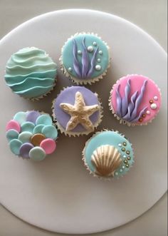 cupcakes decorated in pastel colors with seashells and starfish on top