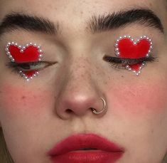 a woman with red and white makeup has hearts painted on her eyes